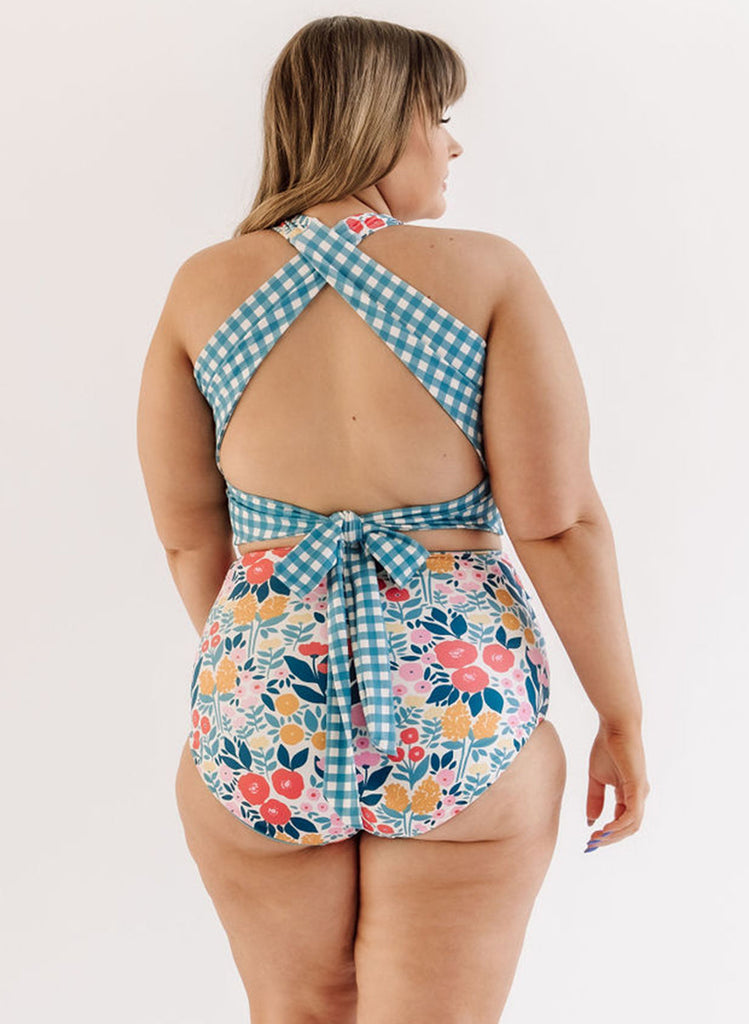 Photo of a woman wearing a May Flowers cross-back swim crop top and a may flowers swim bottom back angle