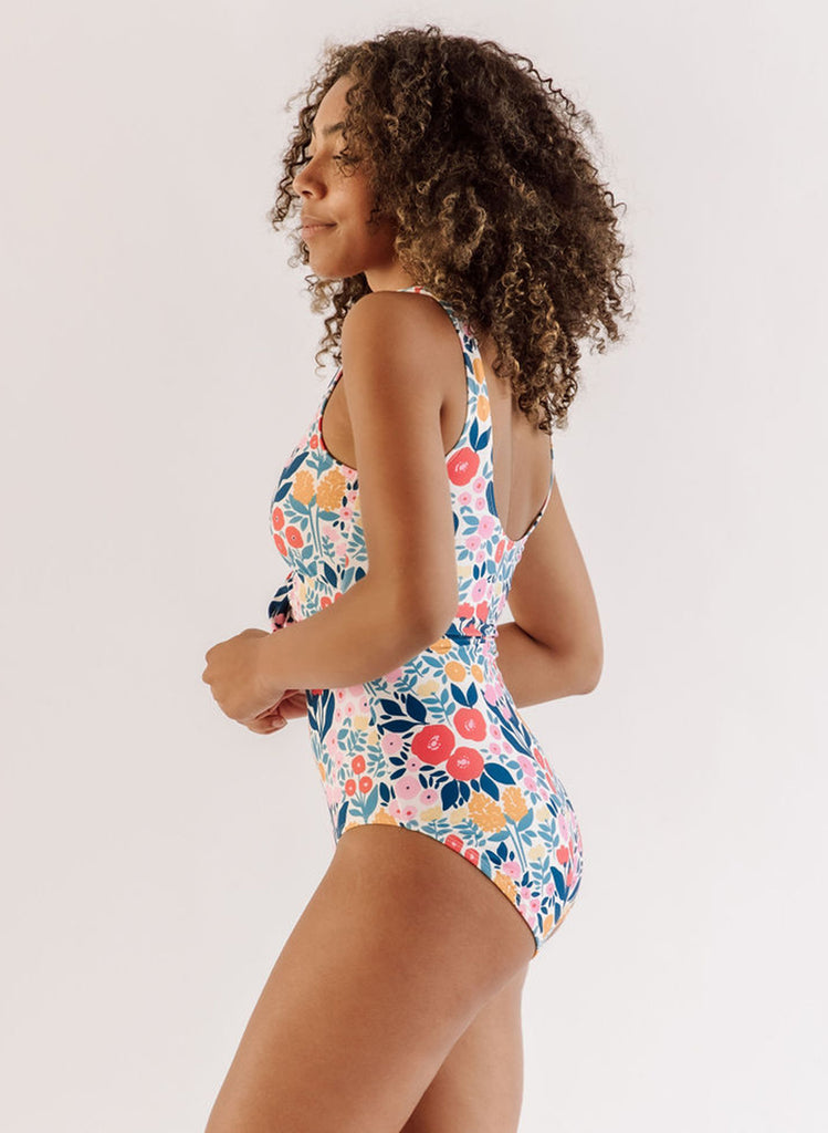 Photo of a woman wearing a May Flowers knotted one-piece swim suit side angle