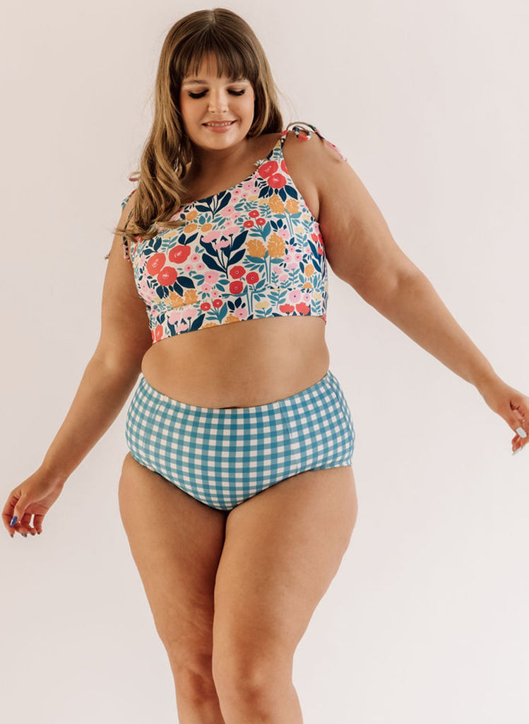 Photo of a woman wearing a may Flowers shoulder-tie swim crop top and a blue and white checkered swim bottom