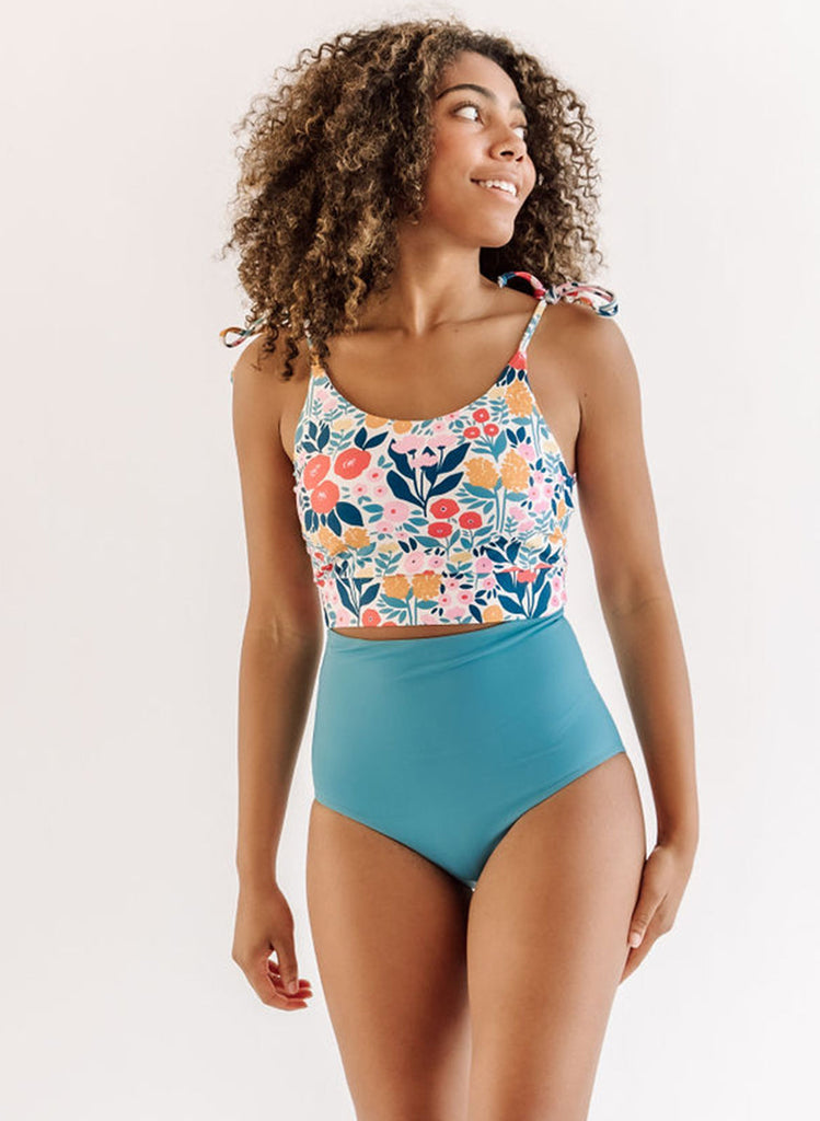 Photo of a woman wearing a may Flowers shoulder-tie swim crop top and a blue swim bottom