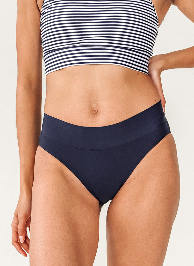 Up close photo of woman wearing a blue and white striped cropped swim top with blue classic low rise swim bottoms