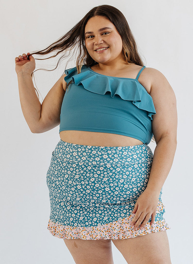 Photo of woman wearing blue ruffle cropped swim top with blue floral swim skirt
