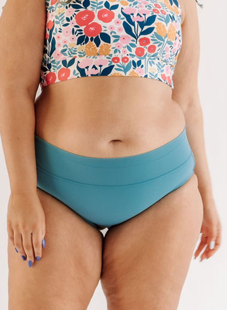 Photo of a woman wearing an Ocean classic swim bottom and a May Flowers swim crop top