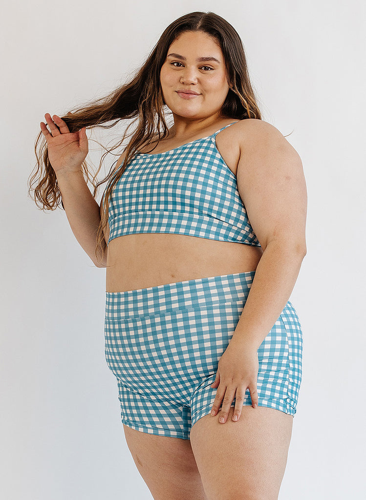 Photo of woman wearing blue and white gingham bralette swim top with blue and white gingham swim shorts