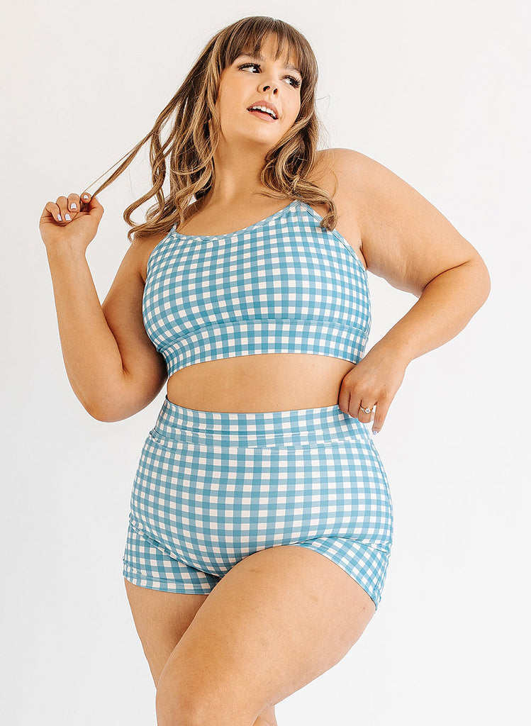 Photo of woman wearing blue and white gingham bralette swim top with blue and white gingham swim shorts