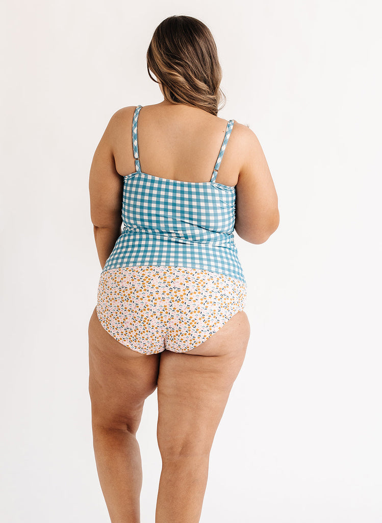 Photo of woman wearing blue and white gingham swim tankini with multi color floral swim bottoms back angle