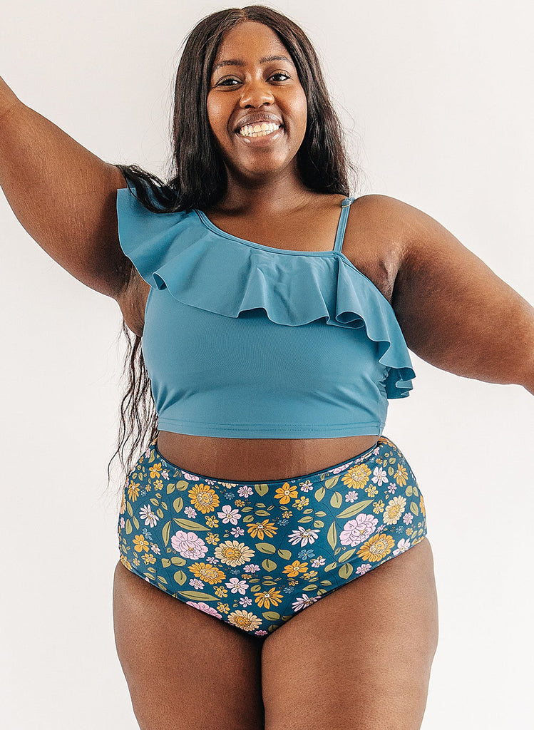 Photo of woman wearing blue ruffle cropped swim top with multi color floral swim bottoms