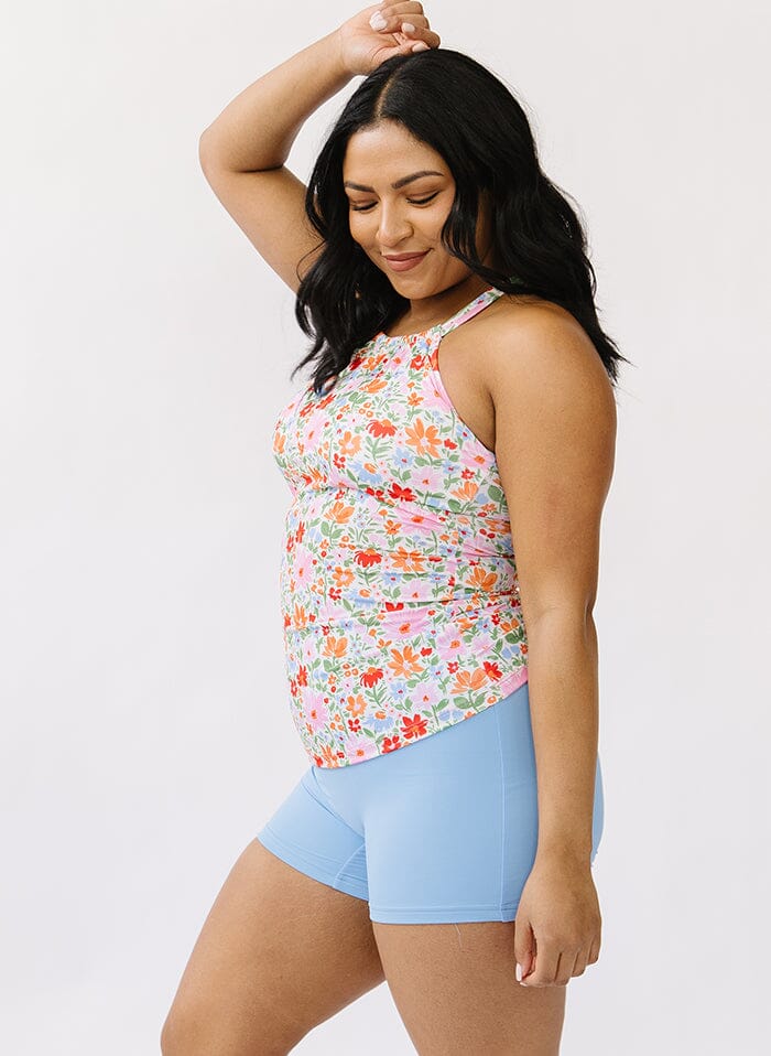 Photo of a woman wearing a floral double cinch swim top and a blue swim short bottom side angle