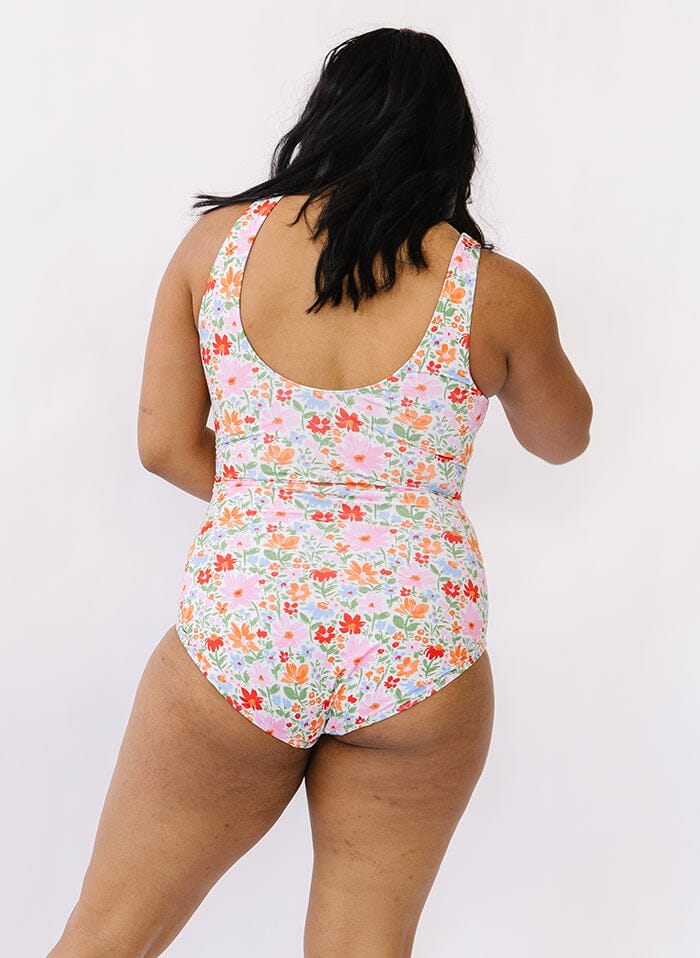 Photo of a woman wearing a floral knotted swim one piece back angle