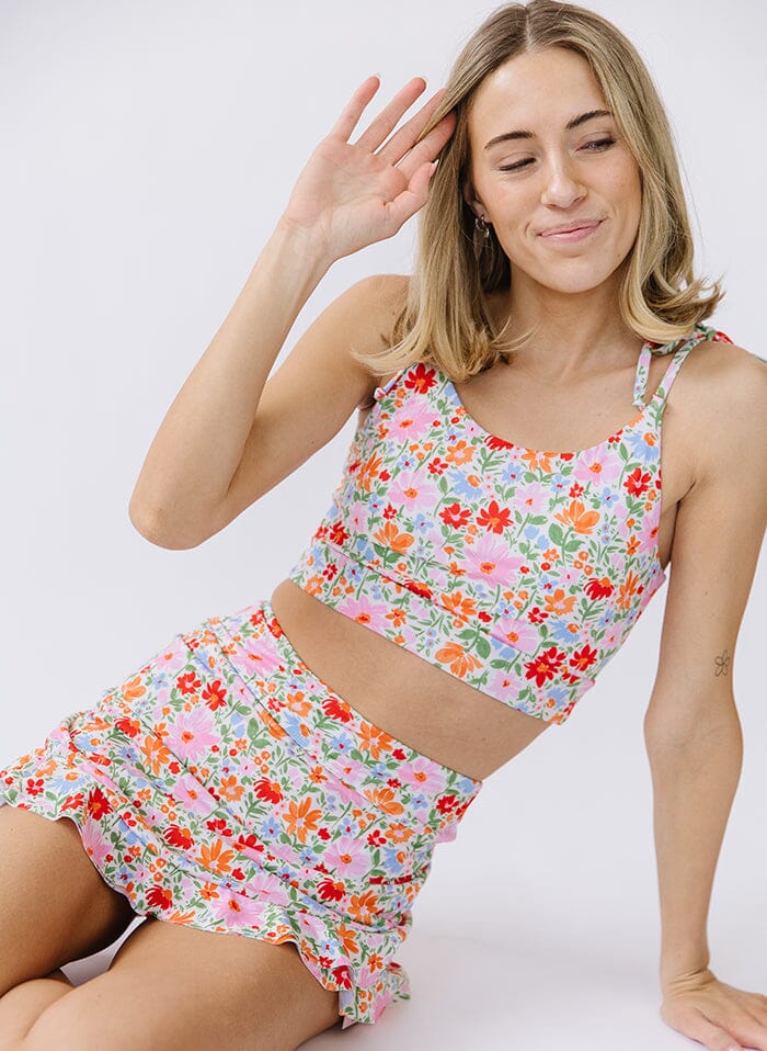 Photo of a woman wearing a floral shoulder-tie swim crop top and a floral swim skirt bottom