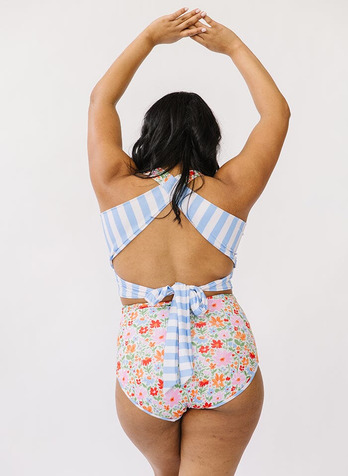 Photo of a woman wearing a multi color swim crop top and floral swim bottoms back angle