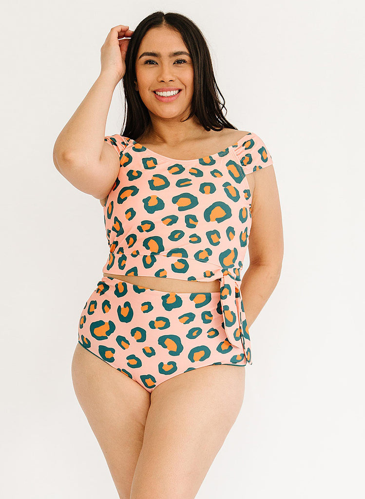 Photo of woman wearing a pink leopard print cropped swim top with pink leopard high waist swim bottoms