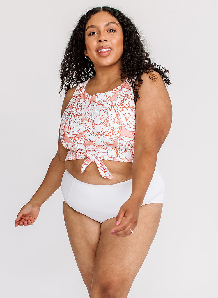 Photo of a woman wearing a pink and white floral swim crop top and a white swim bottom