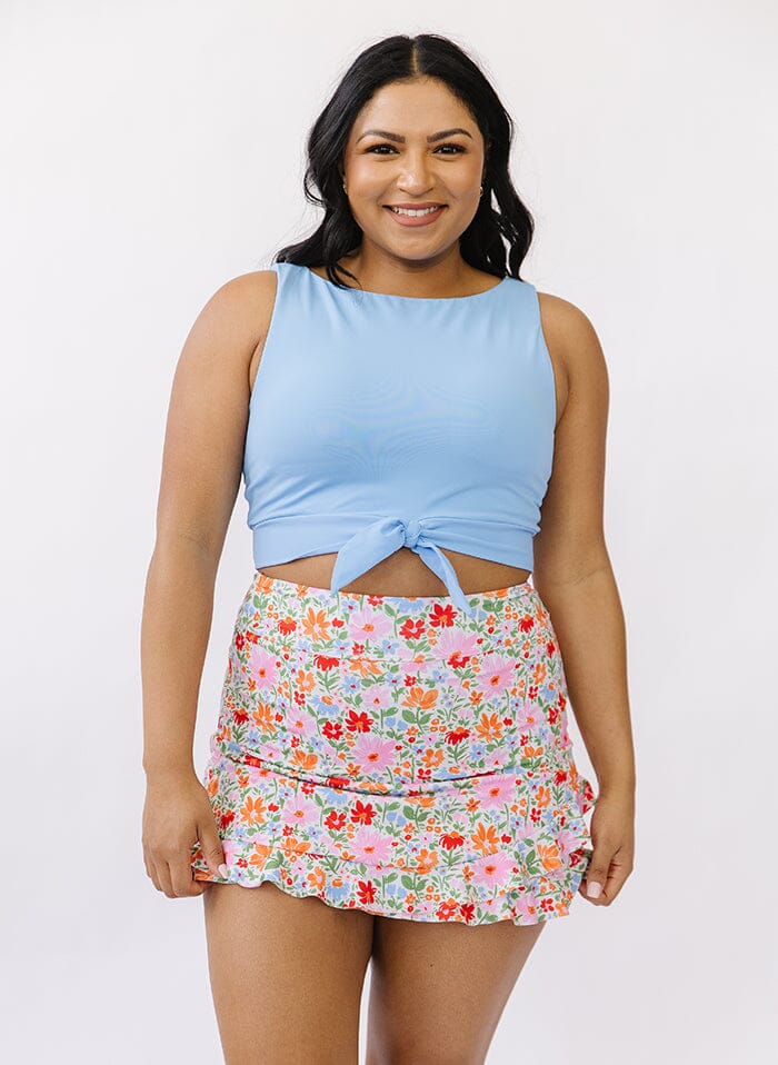 Photo of a woman wearing a floral swim skirt bottom and a blue swim crop top