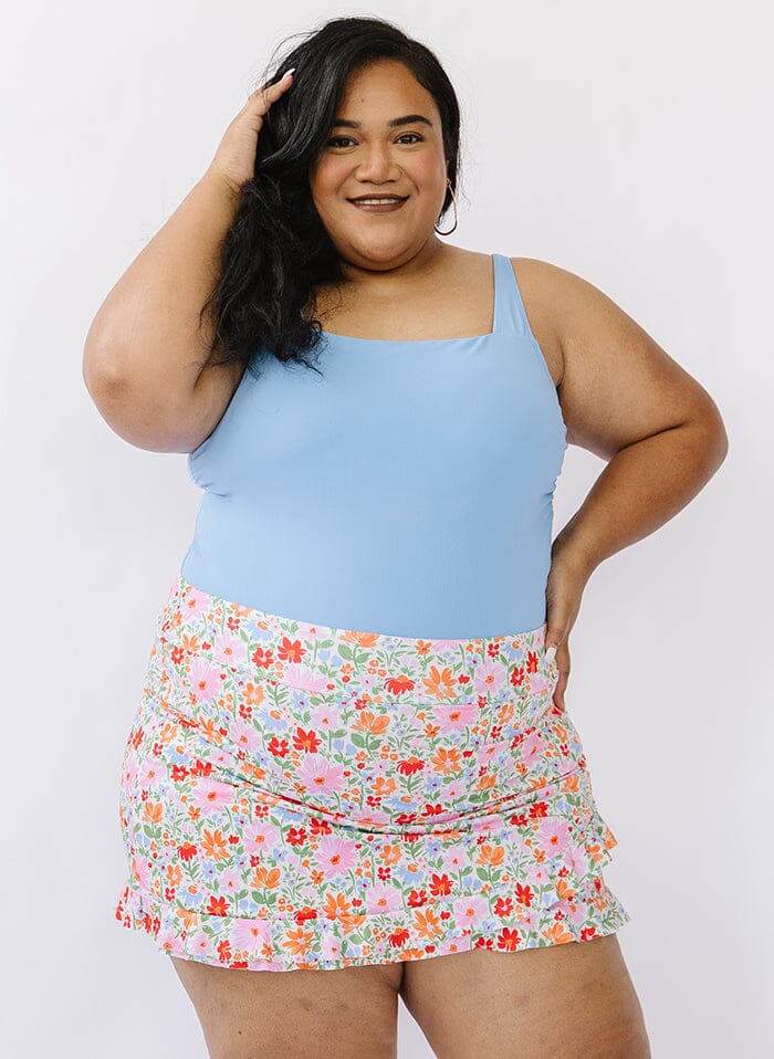 Photo of a woman wearing a floral swim skirt bottom and a blue swim top