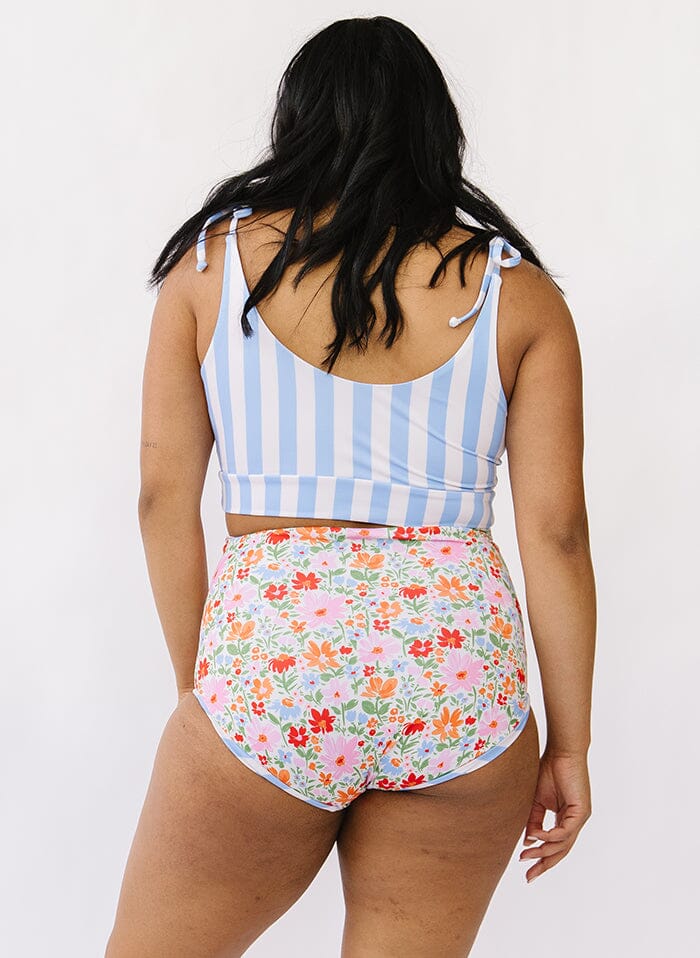 Photo of a woman wearing a peri stripe shoulder-tie swim crop top and a floral swim bottom back angle