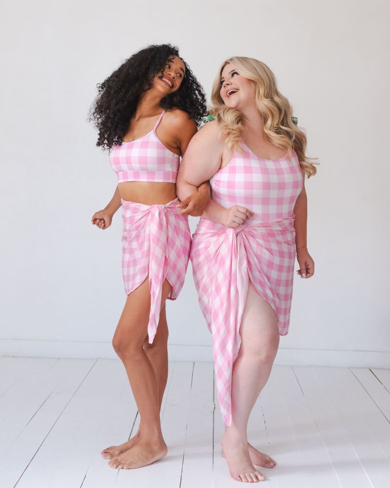 Photo of two women wearing a pink and white checkered Sarong and a pink and white checkered swim suit