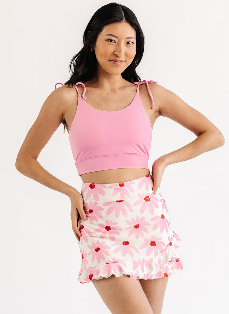 Photo of woman wearing pink cropped swim top with pink and white floral swim skirt