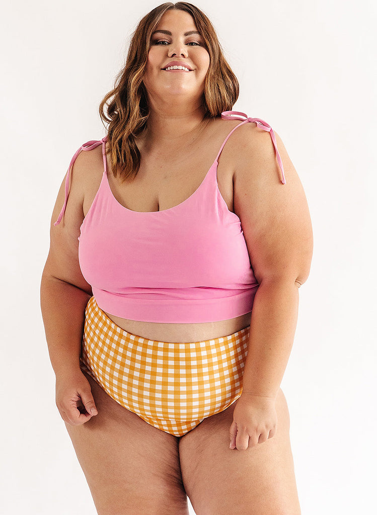Photo of woman wearing pink cropped swim top with yellow and white gingham swim bottoms