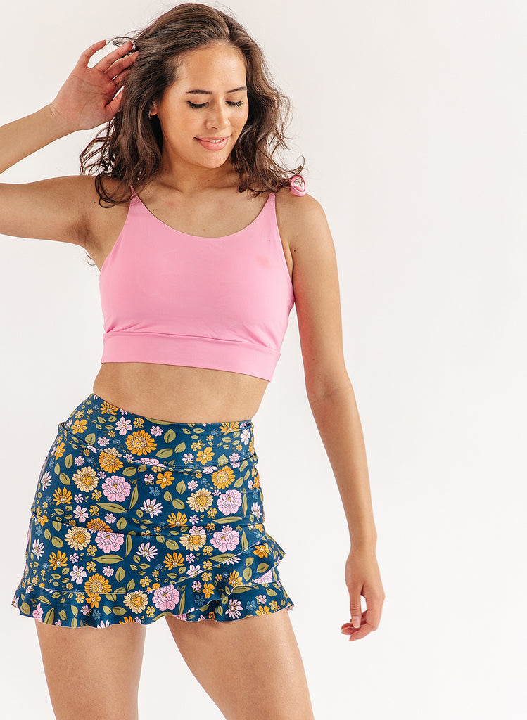 Photo of woman wearing pink cropped swim top and multi color floral swim skirt