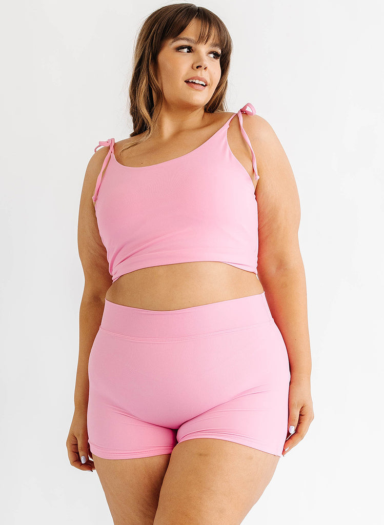 Photo of woman wearing pink cropped swim top with pink swim shorts