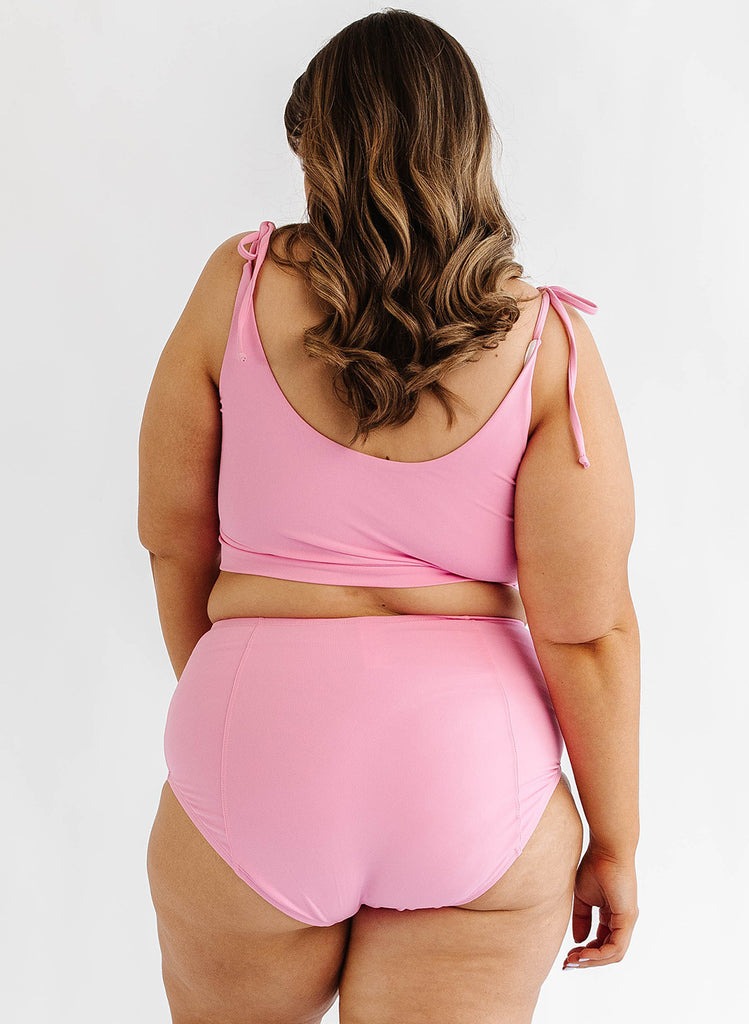 Photo of woman wearing pink cropped swim top with pink swim bottoms back angle