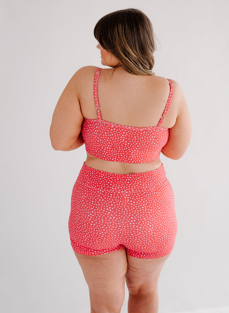 Photo of woman wearing pink dot bralette swim top with pink dot swim shorts back angle