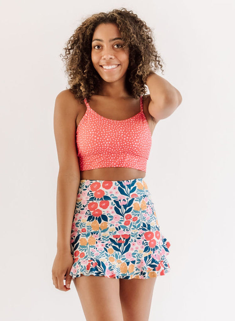 Photo of woman wearing pink dot bralette swim top with multi color floral swim skirt