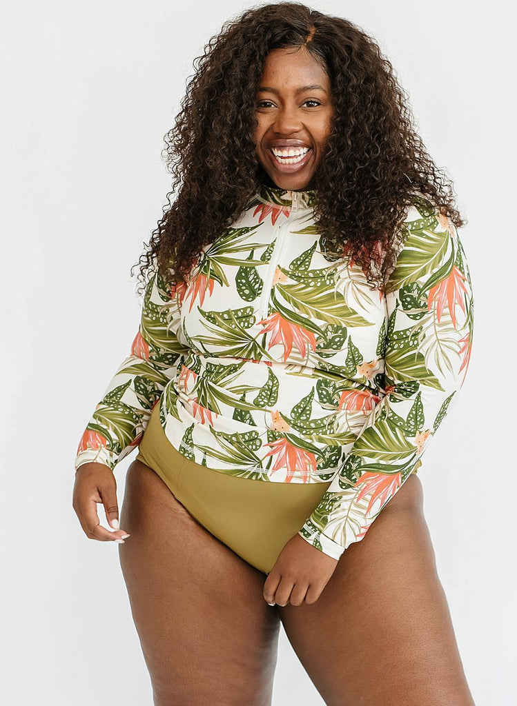 Photo of woman smiling wearing green floral long sleeve swim top with green high waist swim bottoms
