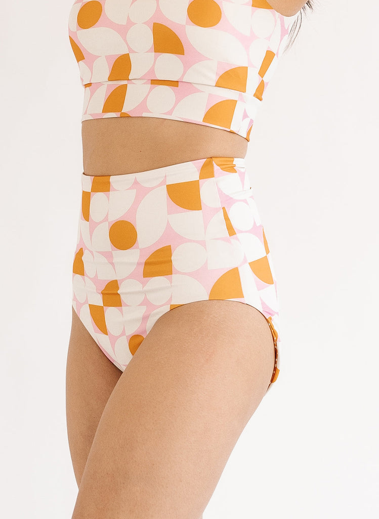 Photo of woman wearing orange and white geometric reversible swim bottoms