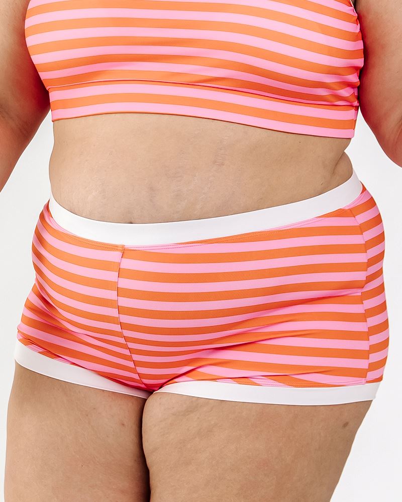 Photo of a woman wearing a Sherbet stripe retro swim short bottom and a Sherbet stripe swim crop top