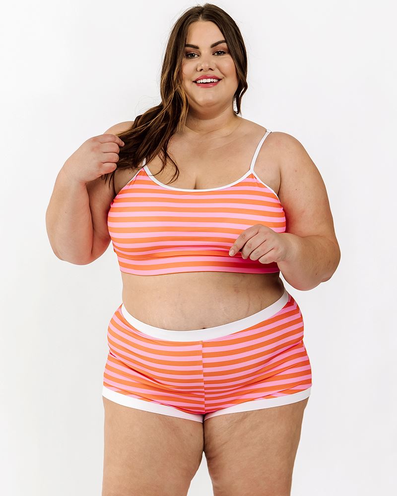 Photo of a woman wearing a Sherbet stripe swim bralette and a sherbet stripe swim short bottom