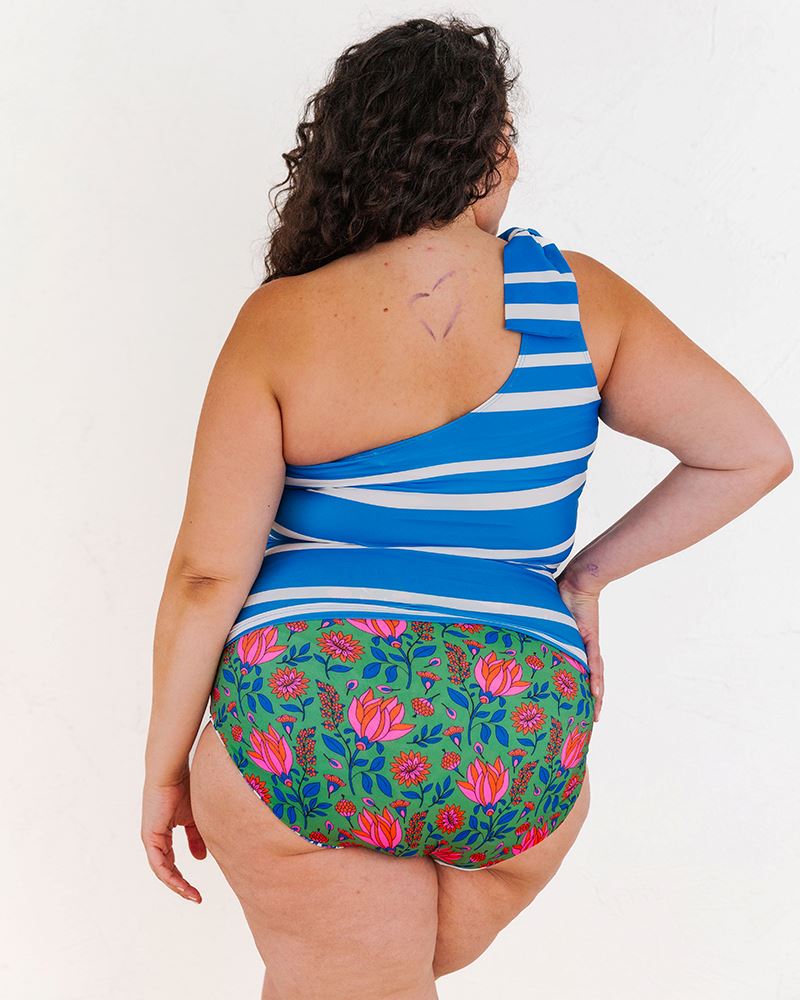 of a woman wearing a Capri one-shoulder swim top and a Fresco floral swim bottom back angle
