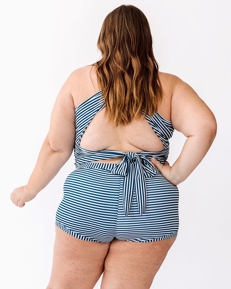 Photo of a woman wearing an Indigo stripe cross-back swim crop top and an Indigo stripe swim short bottom back angle