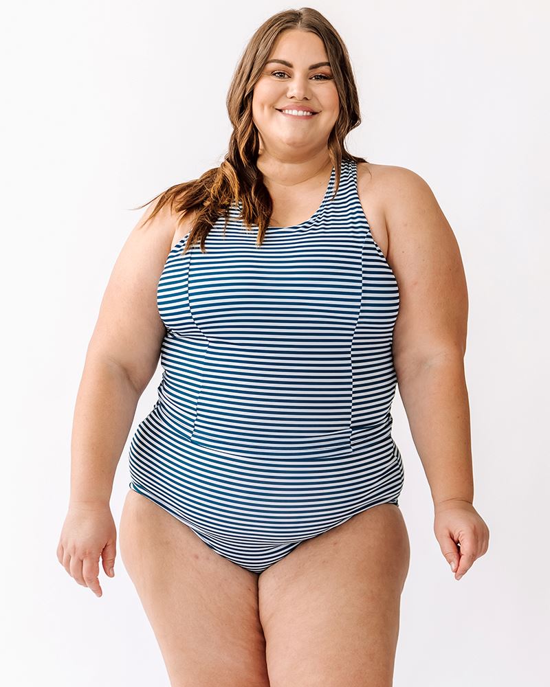 Photo of a woman wearing a June floral/ Indigo stripe reversible swim bottom stripe side and an Indigo stripe swim crop top