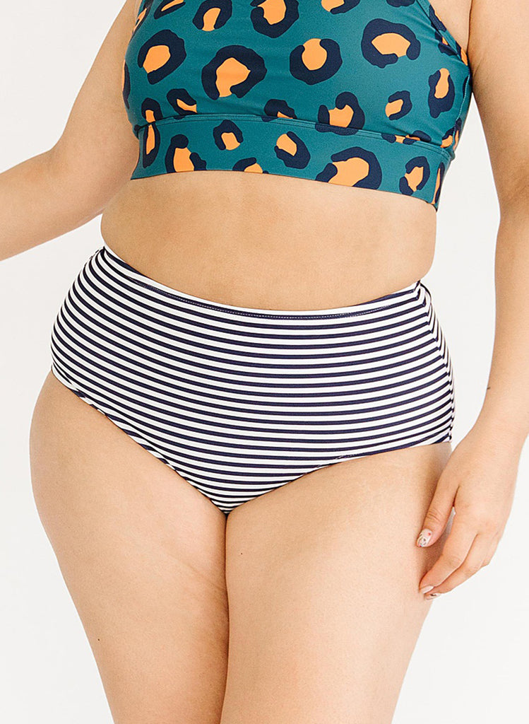 Close up photo of a woman wearing a blue leopard print cropped swim top with blue and white striped high waist swim bottoms