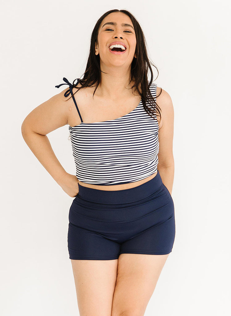 Photo of woman wearing a blue and white striped cropped swim top with blue high waist swim shorts