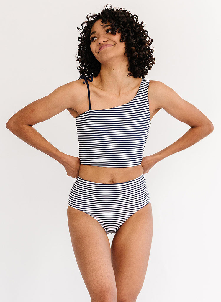 Photo of woman wearing a blue and white striped cropped swim top with blue and white striped high waist swim bottoms