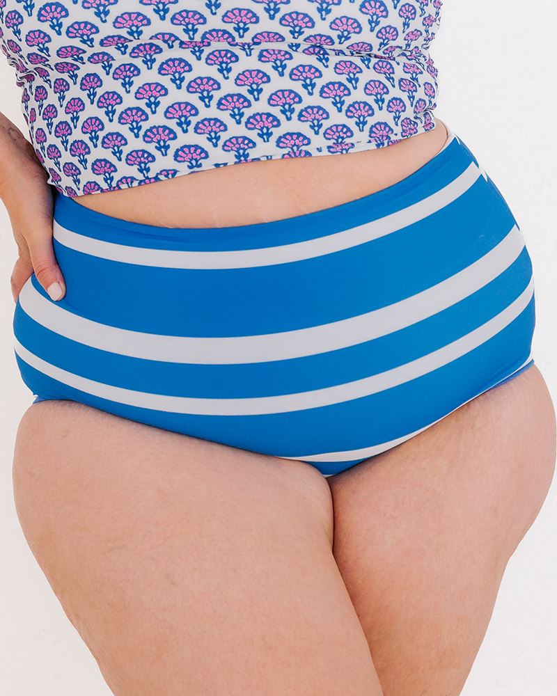 Photo of a woman wearing a Capri/Capri stripe reversible swim bottom stripe side and a Block floral swim crop top