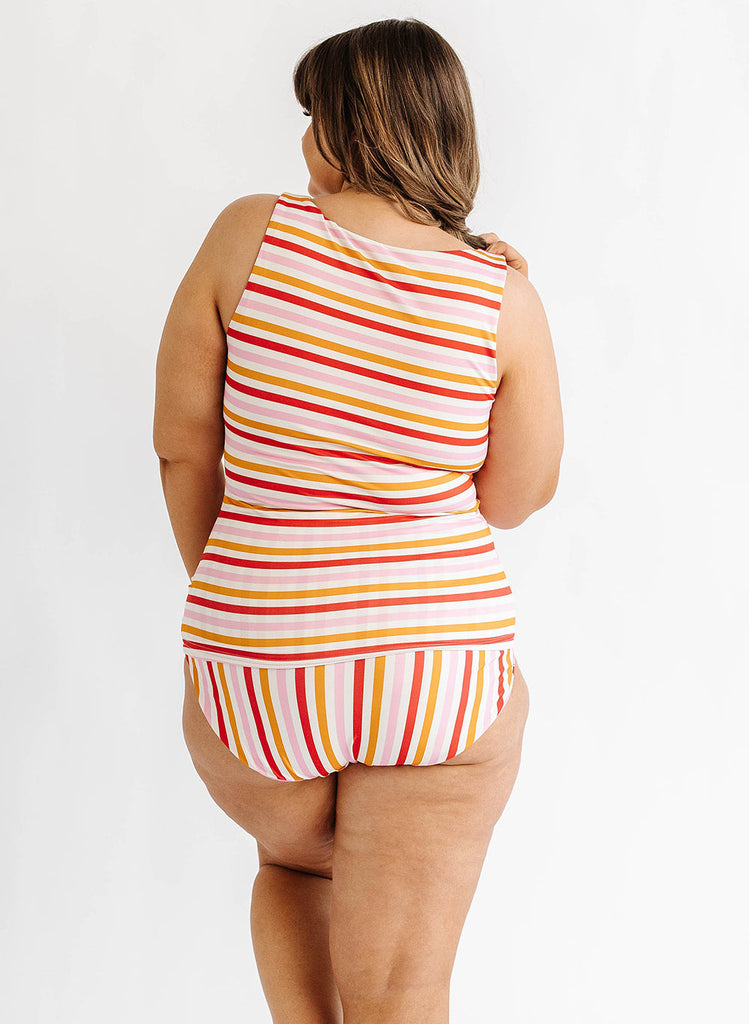 Photo of woman wearing multi color stripe boat neck swim tankini with multi color stripe swim bottoms back angle