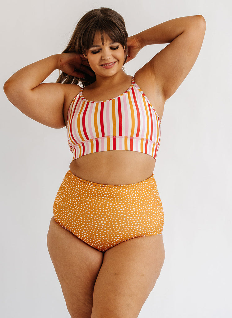 Photo of woman wearing multi color stripe bralette swim top with orange and white dot swim bottoms