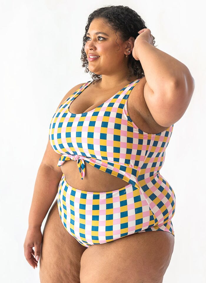 Photo of a woman wearing a multi color checkered one piece swim suit- side angle