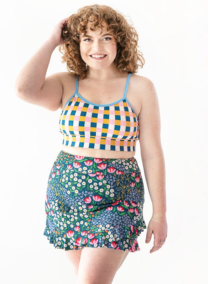 Photo of woman wearing a multi colored checkered cropped swim top with a blue floral swim skirt
