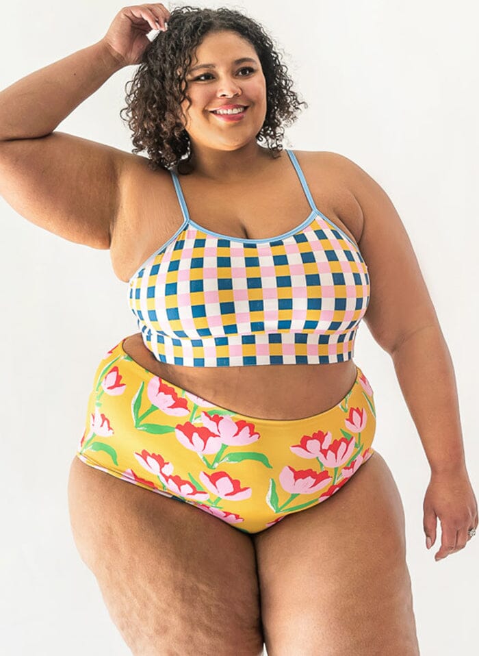 Photo of a woman wearing multi colored checkered cropped swim top with yellow floral high waist swim bottoms
