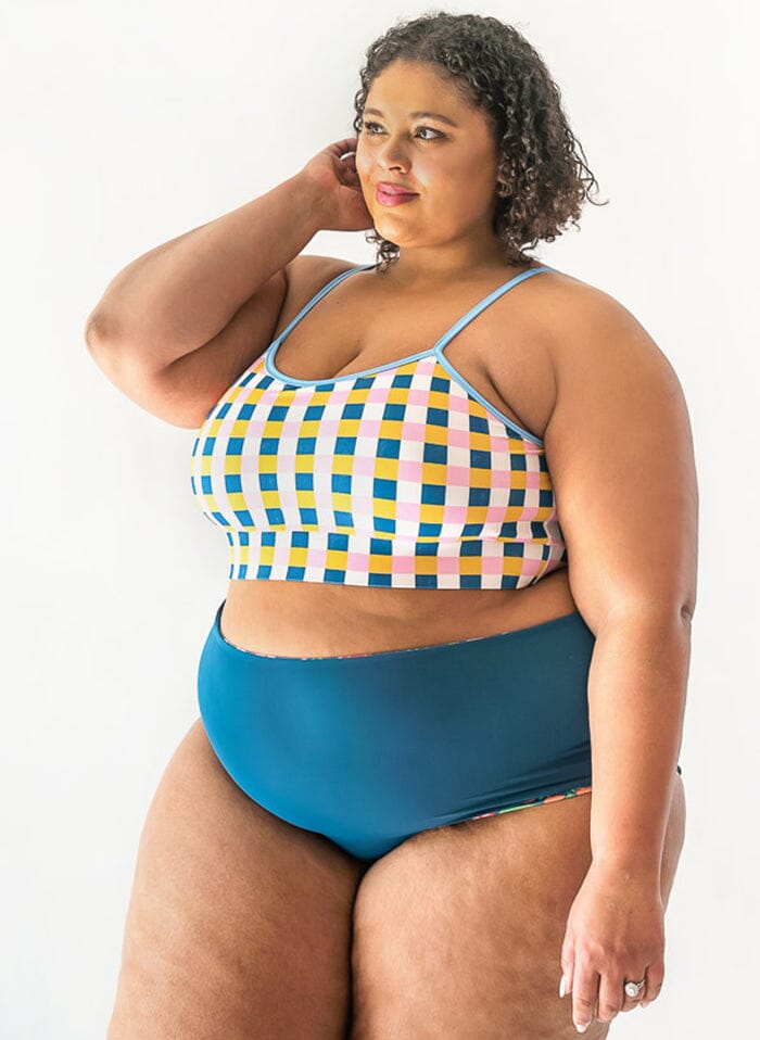 of a woman wearing a Blixen/Indigo reversible swim bottom indigo side and a multi color checkered swim bralette side angle