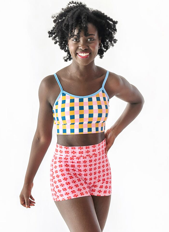 Photo of a woman wearing a multi color checkered swim bralette and pink floral swim shorts