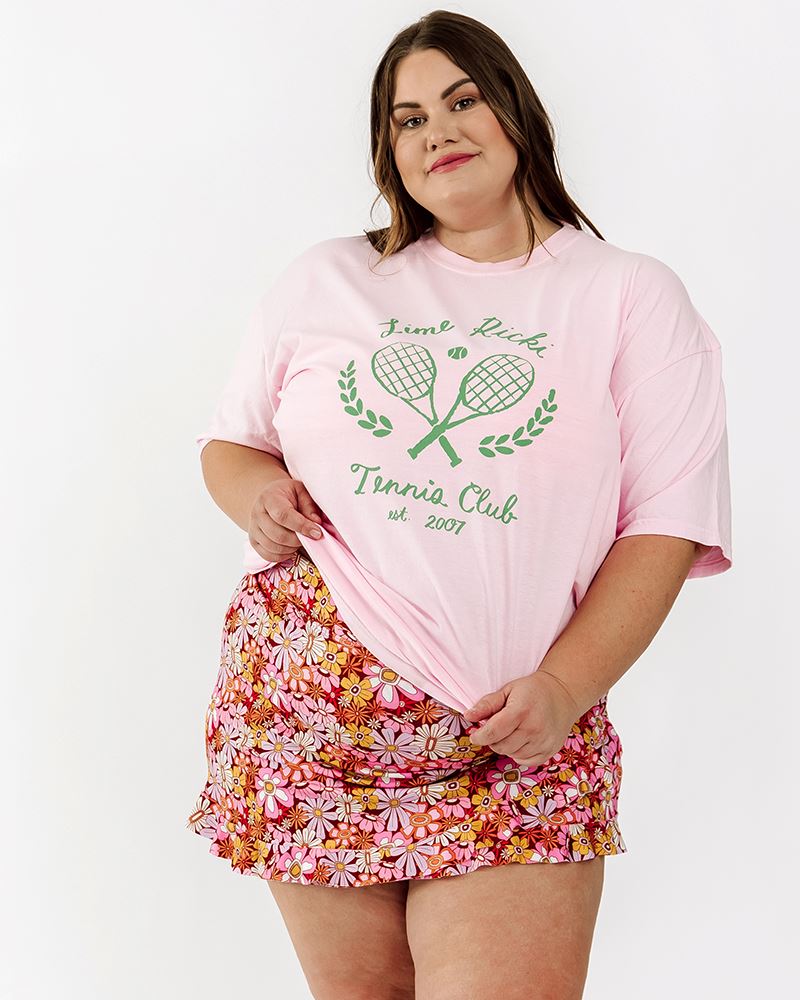 Photo of a woman wearing a groovy Blooms floral swim skirt bottom and a Tennis club tee-shirt