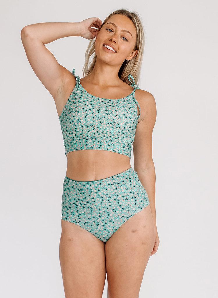 Photo of a woman wearing a blue floral cropped swim top with blue floral high waist swim bottoms