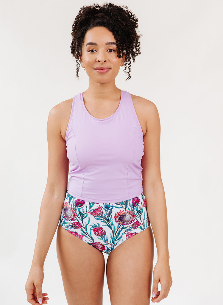 Photo of a woman wearing a lavender swim top and a dessert floral swim bottom