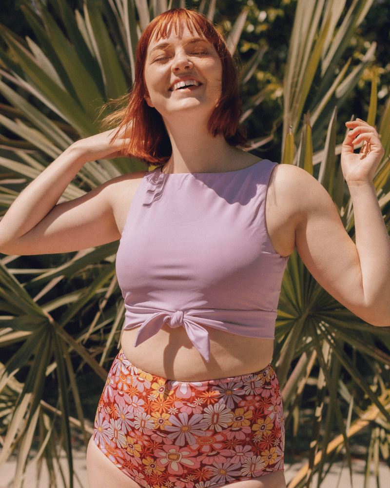 Photo of a woman wearing a Lilac knotted swim crop top and a Groovy Blooms floral swim bottom